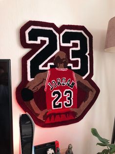 a basketball jersey hanging on the wall next to a computer desk with a lamp and other items