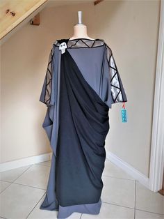 a dress on a mannequin in front of a stair case with a tag hanging from it