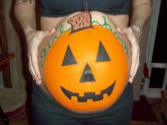 a pregnant woman holding a pumpkin in her belly