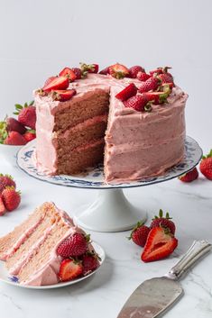 a strawberry layer cake with one slice cut out and the other half on a plate