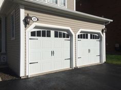 two white garages with clocks on the side of each door and windows above them