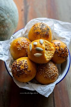 a bowl filled with buns covered in sesame seeds