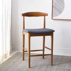 a wooden chair sitting in front of a window next to a painting on the wall