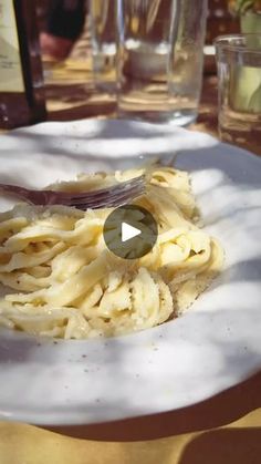 a white plate topped with pasta on top of a table