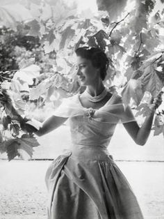 a woman in a dress standing under a tree