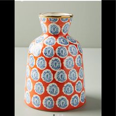 an orange and blue vase sitting on top of a table