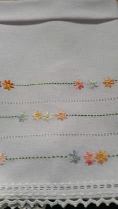 a white table cloth with flowers on the edge and green stitching at the bottom