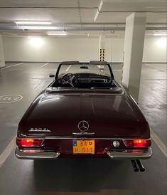 a car parked in a parking garage with its hood up and the back lights on