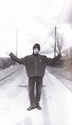 a man standing on the side of a road with his arms outstretched