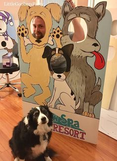 a black and white dog sitting on the floor next to a cardboard cutout of an animal