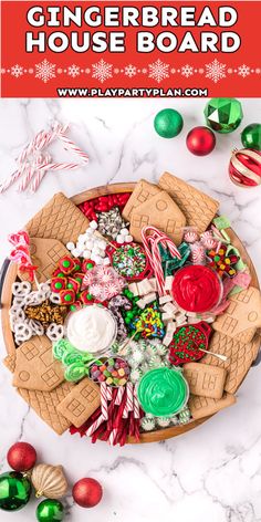 gingerbread house board with candy and candies on it, surrounded by christmas decorations