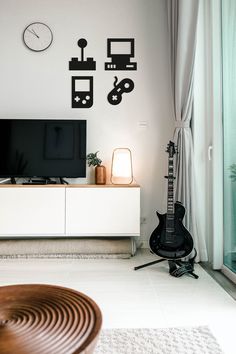 a living room with a guitar on the floor next to a flat screen tv set