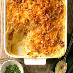 a casserole with meat and cheese in a white dish next to two small bowls