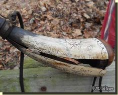 an old metal pipe with writing on it is sitting on a wooden bench in the woods