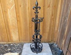 a wrought iron candle holder in front of a wooden fence