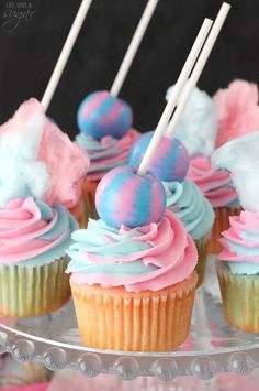 cupcakes with pink, blue and white frosting on a cake plate