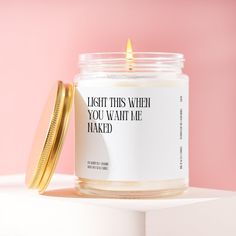 a candle with a quote on it sitting next to a gold container that says, i wish this when you want me naked