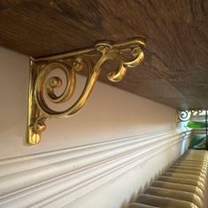 a row of chairs sitting under a wooden ceiling next to a wall with gold brackets on it