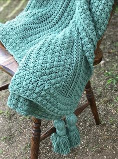 a green blanket sitting on top of a wooden chair