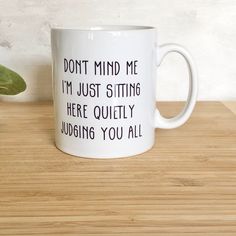 a white coffee mug that says, don't mind me i'm just sitting here quietly judging you all