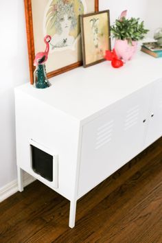 there is a dog house on top of the white cabinet in the room with pictures above it