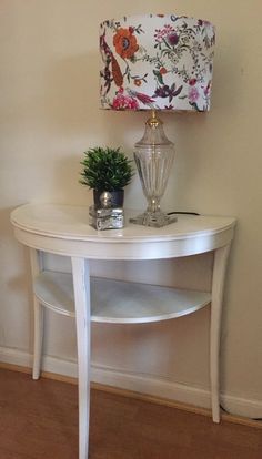 a white table with a lamp on top and a potted plant next to it