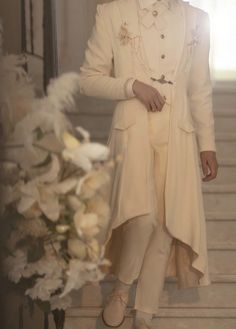 a man in a white suit and hat standing on stairs