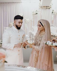 a man and woman standing next to each other in front of a table with flowers