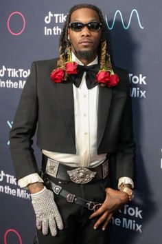 a man in a tuxedo and gloves poses for the camera at an event