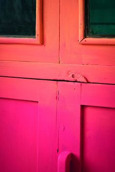 an orange and pink door with two windows