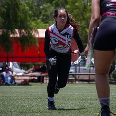 a girl running with a frisbee in her hand while another girl looks on