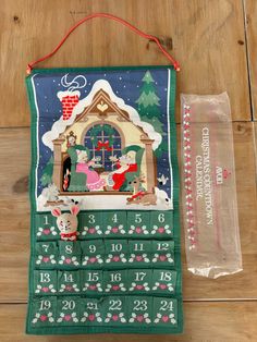 an old fashioned christmas calendar hanging on a wooden floor with a bag next to it