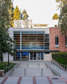 the entrance to an office building with stairs leading up to it and trees in front