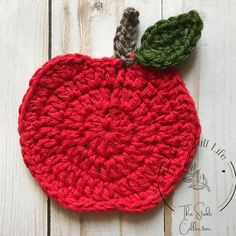 a crocheted apple with a green leaf on the top and red yarn around it