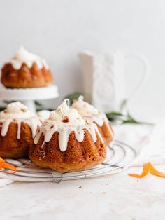 three bundt cakes sitting on top of a wire rack next to orange peels