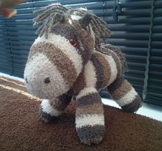 a stuffed zebra sitting on top of a brown rug next to a window with blinds