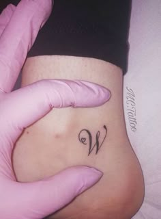 a woman's stomach with a small tattoo on her belly and the letter w