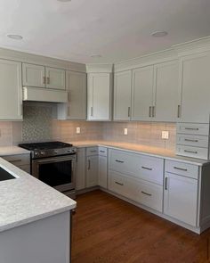 an empty kitchen with white cabinets and wood floors