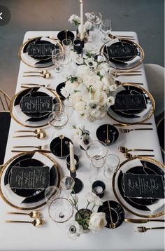 the table is set with black and white plates, silverware, and floral centerpieces