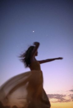 a woman in a white dress is throwing a frisbee