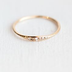 a gold ring with three small diamonds on the top and bottom, sitting on a white surface