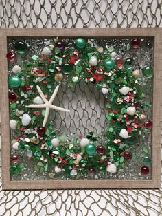 a christmas wreath made out of glass beads and other ornaments in a frame on a wall