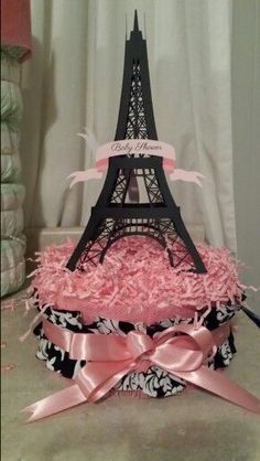 there is a cake that looks like the eiffel tower with pink ribbons on it