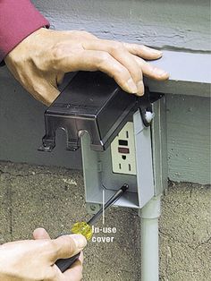 a person is fixing an electrical outlet on the side of a house with their hands