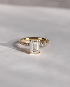 an emerald cut diamond engagement ring with pave diamonds