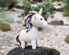 a crocheted unicorn sitting on top of a rock