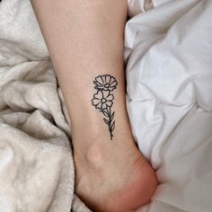 a woman's foot with a small flower tattoo on the left side of her leg