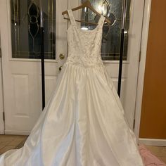 a wedding dress hanging on a hanger in front of a door