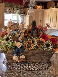 a scarecrow sitting on top of a wooden boat filled with flowers and pumpkins