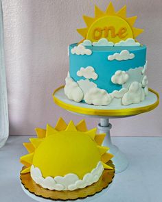 two tiered cakes with sun and clouds on top, one is blue and the other is yellow